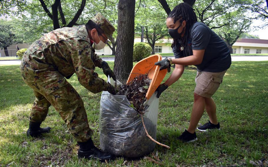 Sgt. Jennifer Jackson, right, Camp Zama’s Better Opportunities for Single Soldiers president, and 1st Lt. Naoki Kumagai, assigned to the 4th Engineer Group, Japanese Ground Self-Defense Force, work together to clean up the area around the Otakebi torii during a BOSS community outreach initiative at Camp Zama, Japan, May 27. (Photo Credit: Winifred Brown)