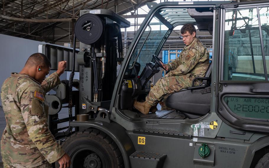 A U.S. Army Soldier from Camp Zama, Japan helps guide a forklift onto a scale for equipment loading training at Yokota Air Base, Japan, May 1, 2023. This Joint training exercise refreshed U.S. Army soldiers from Camp Zama on pallet building procedures and equipment loading, hosted by Airmen from Yokota. (U.S. Air Force photo by Airman 1st Class Jarrett Smith)