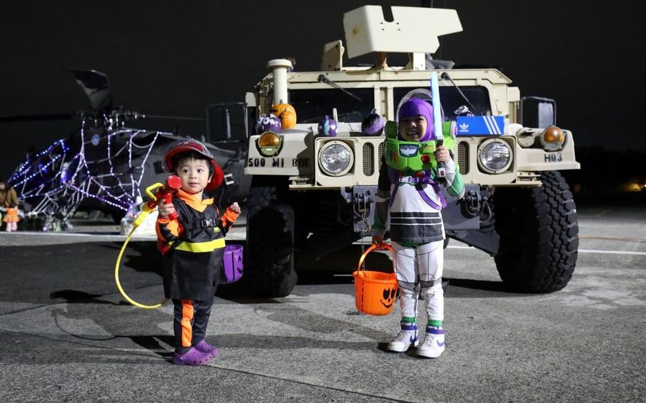 Children dressed as a firefighter and Buzz Lightyear pose for a photo in front of a Humvee during the combined “Trunk-or-Treat” and “Haunted Hangar” event.