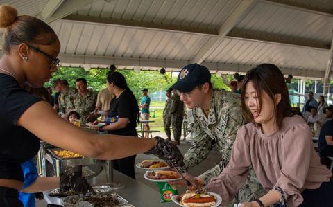 Photo Of Commander, Fleet Activities Sasebo (CFAS) Sailors and community members serve and receive food during a command picnic at Nimitz Park in Sasebo, Japan.