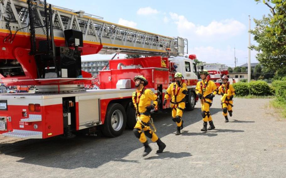 Firefighters assigned to U.S. Army Garrison Japan’s Directorate of Emergency Services run to the rescue of a role-player stranded on the roof of a building as part of a scenario during the city of Zama’s disaster prevention drill Sept. 7.