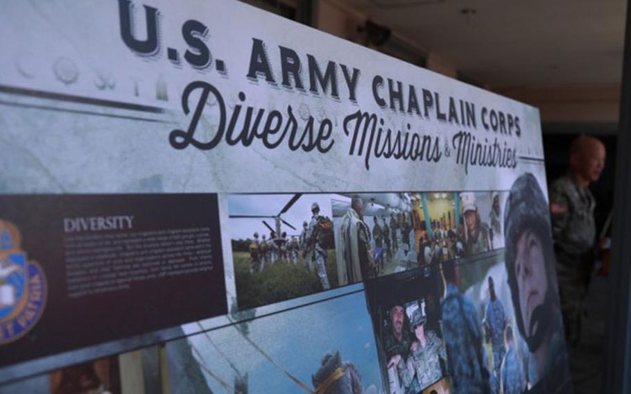 A placard highlighting the U.S. Army Chaplain Corps’ diverse mission and ministries is displayed during the 246th U.S. Army Chaplain Corps anniversary celebration, held July 29 in the Zama Chapel courtyard on Camp Zama, Japan. U.S. Army Japan Command Chaplain (Col.) Steve Shin, far right, gives remarks during the event. (Photo Credit: Dustin Perry, U.S. Army Garrison Japan Public Affairs)