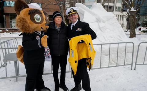 Photo Of Commander, Fleet Activities Yokosuka’s (CFAY) mascot Yokopon, left, and U.S. Navy Lt. Cmdr. Seth Koenig, public affairs officer for Commander, Task Force 70 (CTF 70), pose for a photo with a festival goer during the 75th Annual Sapporo Snow Festival.