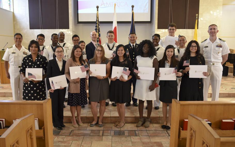 YOKOSUKA, Japan (Aug. 22, 2019) – Seventeen Sailors and spouses from 11 different countries pose for a group photos during a naturalization ceremony at the main chapel onboard Commander, Fleet Activities Yokosuka (CFAY). CFAY provides, maintains, and operates base facilities and services in support of 7th Fleet's forward-deployed naval forces, 71 tenant commands, and 27,000 military and civilian personnel. (U.S. Navy photo by Mass Communication Specialist 2nd Class Tyler R. Fraser)