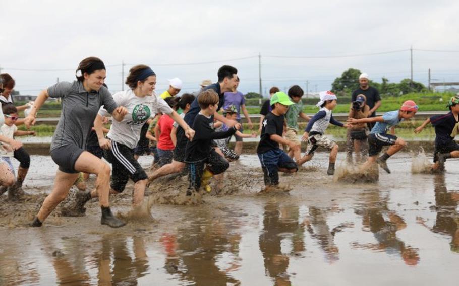 Camp Zama community members join a muddy foot race in a rice paddy before a rice-planting event the Zama International Association hosted June 2 near the installation.