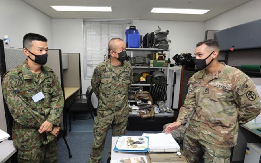 Master Sgt. Juan Polanco, right, noncommissioned officer in charge of preventive medicine at Public Health Command-Pacific, briefs Warrant Officer Masanobu Murawaki, center, the sergeant major of the Japan Ground Self-Defense Force, during his visit to Camp Zama, Japan, Aug. 16, 2022. Murawaki took part in an installation tour to better understand how American and Japanese partners interact in the Cooperative Work Program. (Photo Credit: Sean Kimmons)