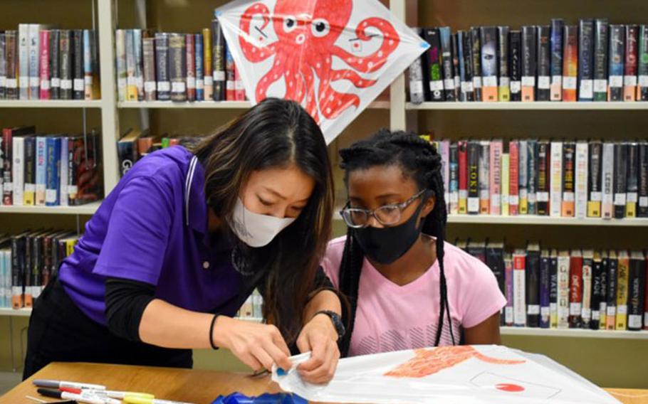 Sari Sugai, left, Camp Zama Army Community Service Exceptional Family Member Program and New Parent Support Program coordinator, helps Alyssa Turner, 12, make a kite during a “Fun Friday” event at the Sagamihara Family Housing Area Library, SFHA, Japan, May 28. (Photo Credit: Winifred Brown)