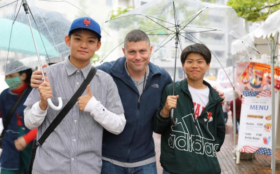 Lt. Col. Michael Gallucci, center, commander of the 10th Support Group Ammunition Depot, poses for a photo with local eventgoers April 29 during the 66th Kure Port Festival in Hiroshima Prefecture. U.S. Army Garrison Japan and 10th SG personnel sold American-style concessions from a booth at the festival. (Noriko Kudo)