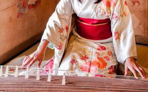 A woman with a kimono plays the koto.