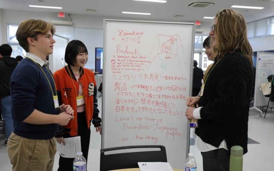 Carson Hansen, left, a junior at Zama Middle High School, discusses a project with his teammates during the student educational exchange and dialogue event.