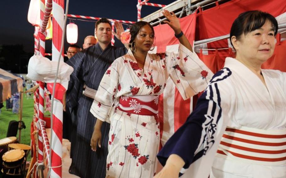 Capt. Chase Martin, left, and Kenesha Chandler, center, both assigned to I Corps (Forward), right, dance together with other unit members and locals on the Bon tower at the 65th Bon Dance Festival held Aug. 3 at Camp Zama, Japan.