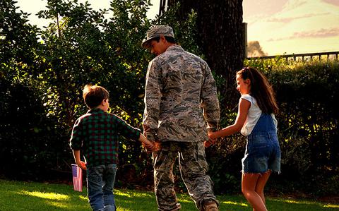 Photo Of a father in military uniform and two children holding hands