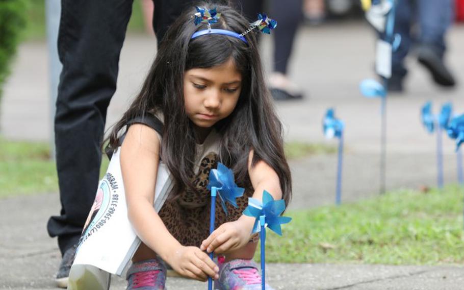 Xiamara Ramos plants a pinwheel in front of the library at Sagamihara Family Housing Area, Japan, during an event in support of National Child Abuse Prevention Month April 30, 2024.