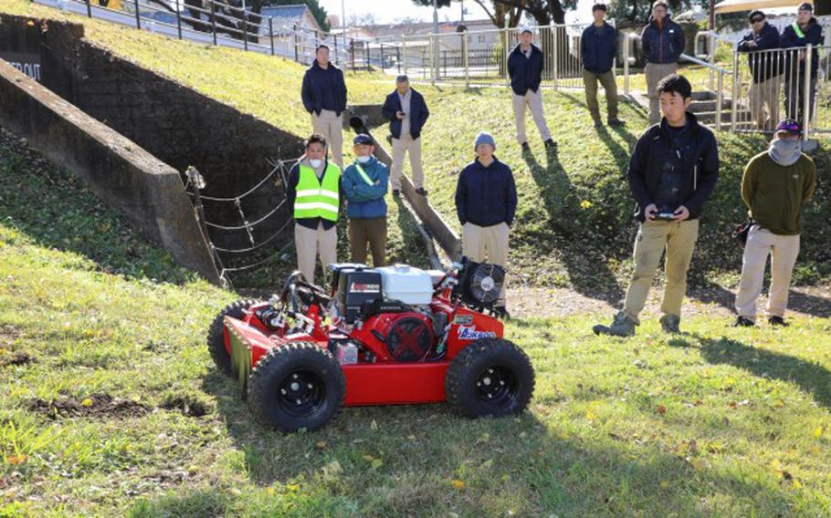 A vendor demonstrates a Sanyokiki remote-controlled lawnmower to Directorate of Public Works employees.