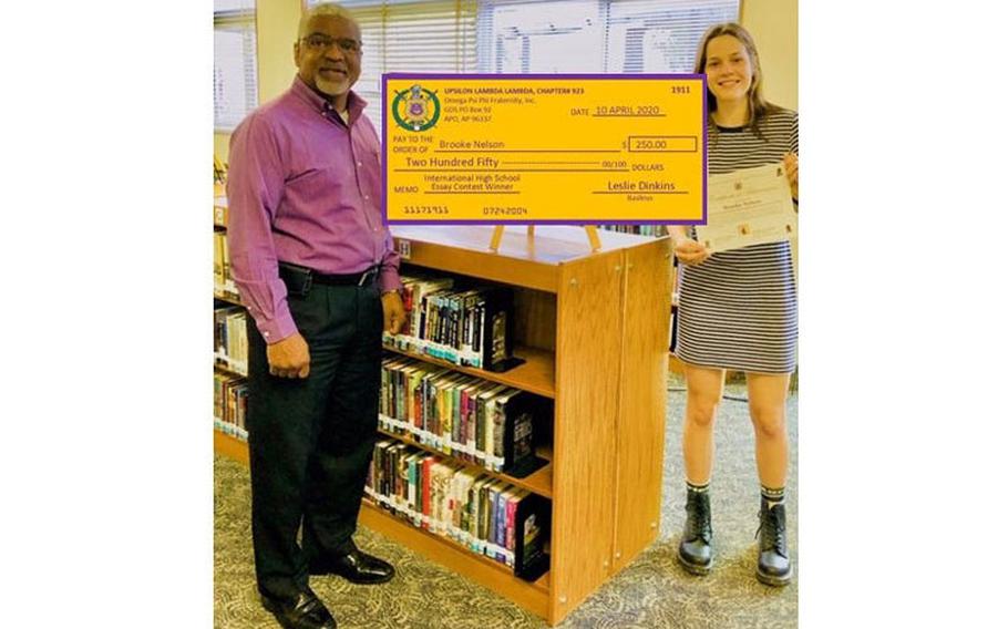 Mr. Andre Sterling of Upsilon Lambda Lambda Chapter presenting $250 scholarship check from the 13th International District of Omega Psi Phi Fraternity, Inc. to Ms. Brooke Nelson, high school senior at Zama Middle High School in Zama, Japan.