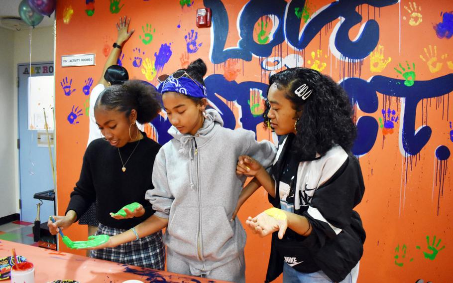 From left, Midori Robinson, Kyleigh Rose and Keisha McNeill paint their hands so they can put a handprint on the “Love is Respect” mural during the Camp Zama Youth Center Teen Dating Violence Awareness Lock-In at Camp Zama, Japan, Feb. 7, 2020.