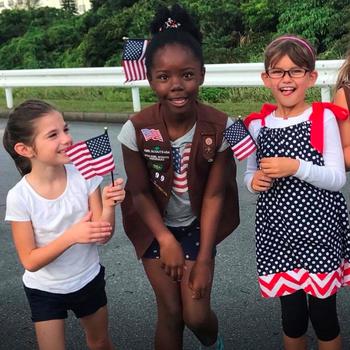 Madeline Embler, Cara Wilson, and Hannah Pawelski (Brownie troop, Girl Scouts of the USA) proudly march in the Veterans’ Day parade at Kadena Air Base, honoring those who served.