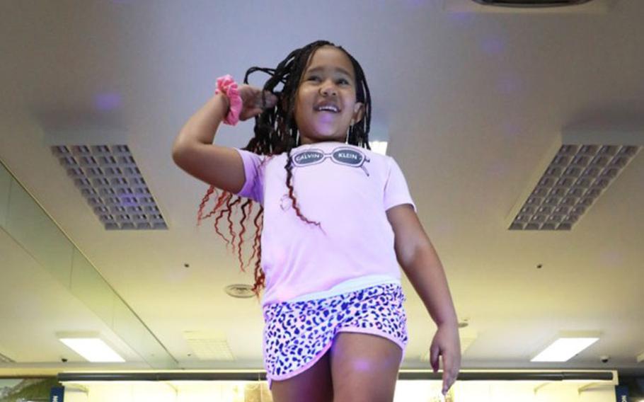 Eliza Boston, 6, flips her hair while posing at the edge of the runway in her selected outfit during a back-to-school fashion show held Saturday at the Main Exchange at Camp Zama, Japan. Camp Zama’s Army Community Service put together the event primarily as a way to show off the many different boys’ and girls’ clothing styles available at the Exchange to those families who arrived to Japan over the summer. (Photo Credit: Dustin Perry, U.S. Army Garrison Japan Public Affairs)