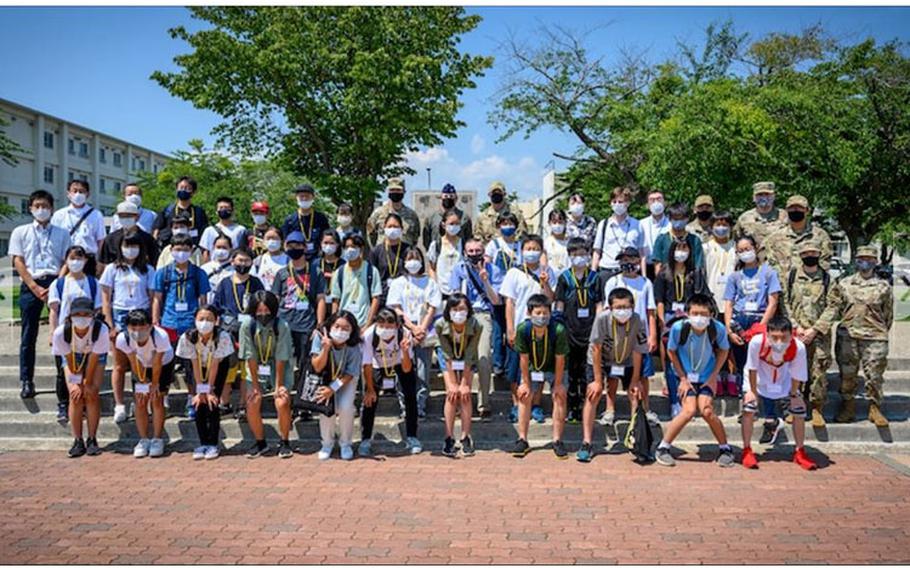 Misawa City English Camp students take a photo with members of Team Misawa during a base tour at Misawa Air Base, Japan, Aug. 3, 2021. During the tour, students interacted with base leadership and were able to ask questions to better understand the Misawa AB mission. (U.S. Air Force photo by Senior Airman China M. Shock)