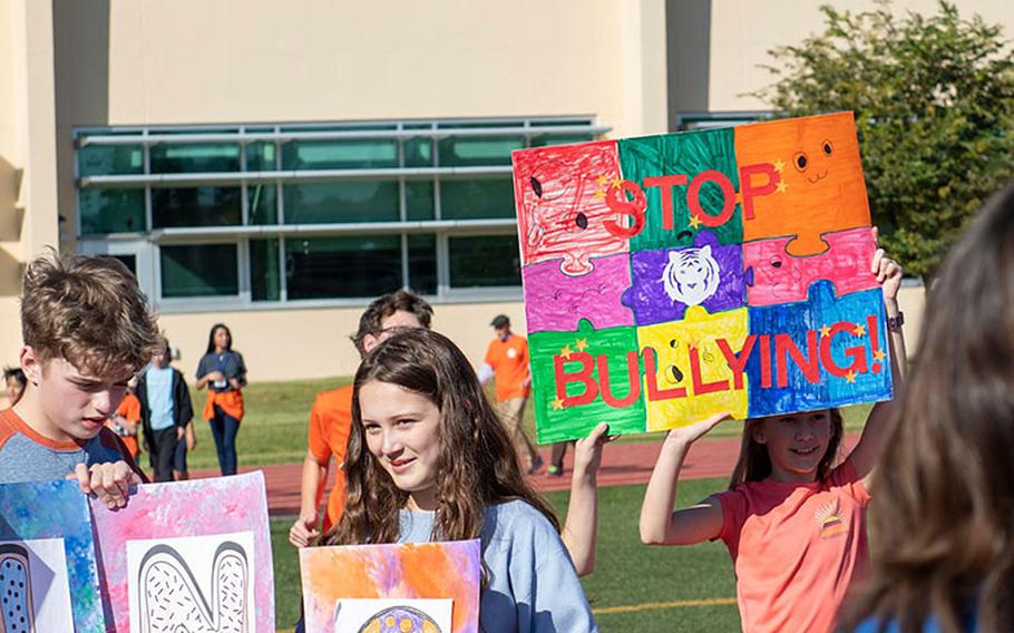 Yokota students hold colorful signs while walking along the Yokota High School track, Oct. 26, 2023, during the Yokota Walk Against Bullying at Yokota Air Base, Japan. Students, teachers, and community members continuously walked the track in support of ending bullying while music and anti-bullying messages played over a loudspeaker. (U.S. Air Force photo by Senior Airman Hannah Bean)