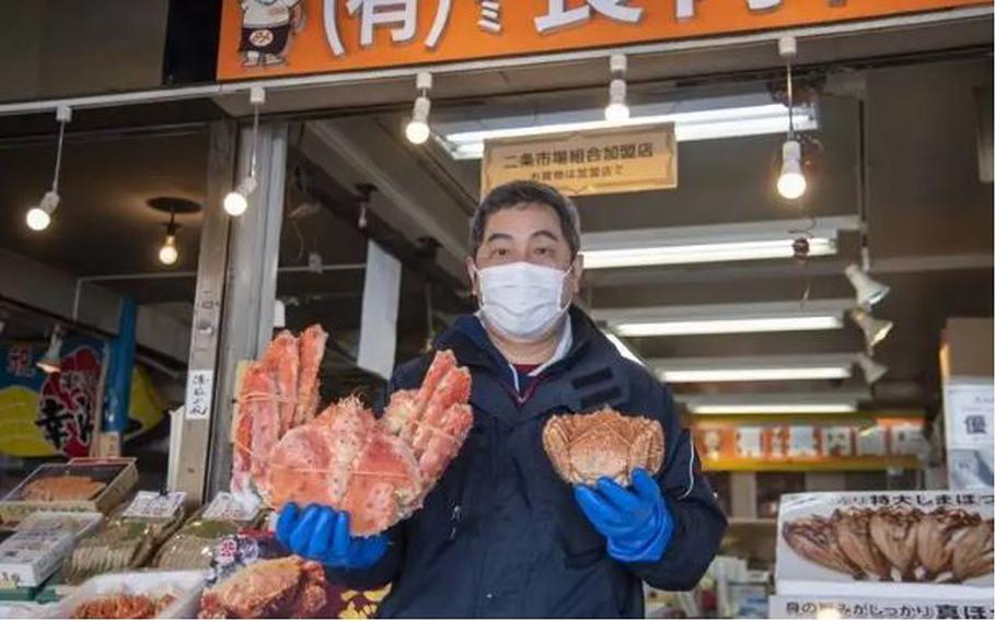 a man holding two different kinds of crabs