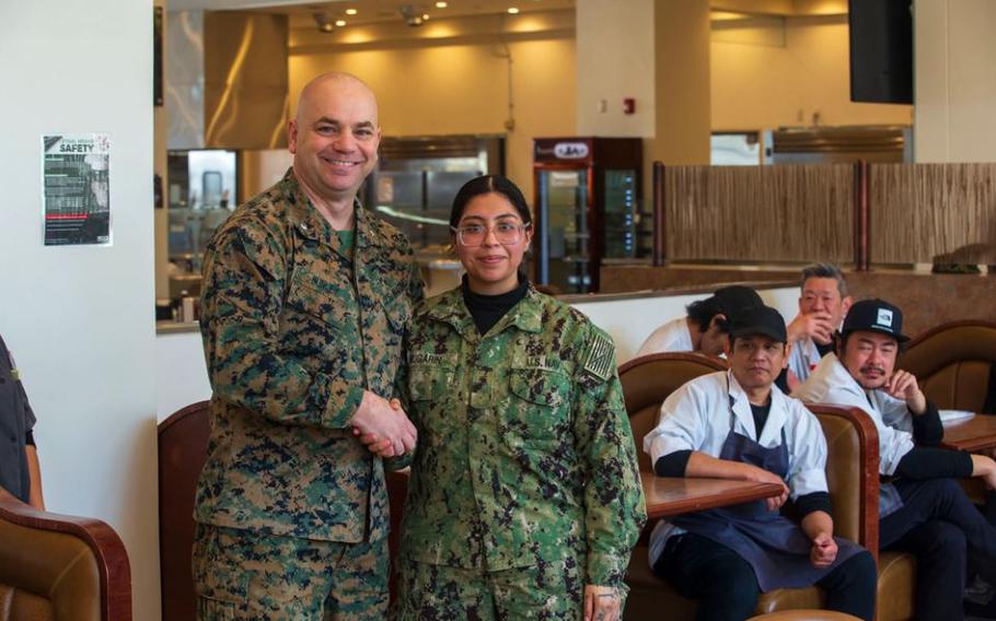 U.S. Marine Corps Lt. Col David Hunley, left, the director of food services for Marine Corps Installations Command, poses for a photo with U.S. Navy Commissaryman Seaman Recruit Leticia Bugarin with Headquarters and Headquarters Squadron, Marine Corps Air Station Iwakuni, after giving her a challenge coin for outstanding work while taking part in the Maj. Gen. William Pendleton Thompson (W.P.T.) Hill memorial awards program, at MCAS Iwakuni, Japan, Jan. 29, 2024.