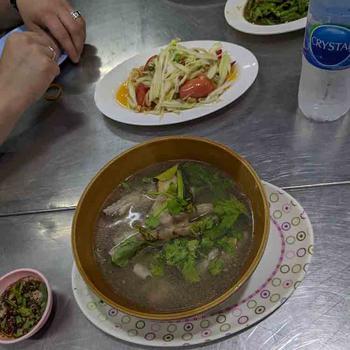 Papaya salad in background, chicken feet soup in foreground