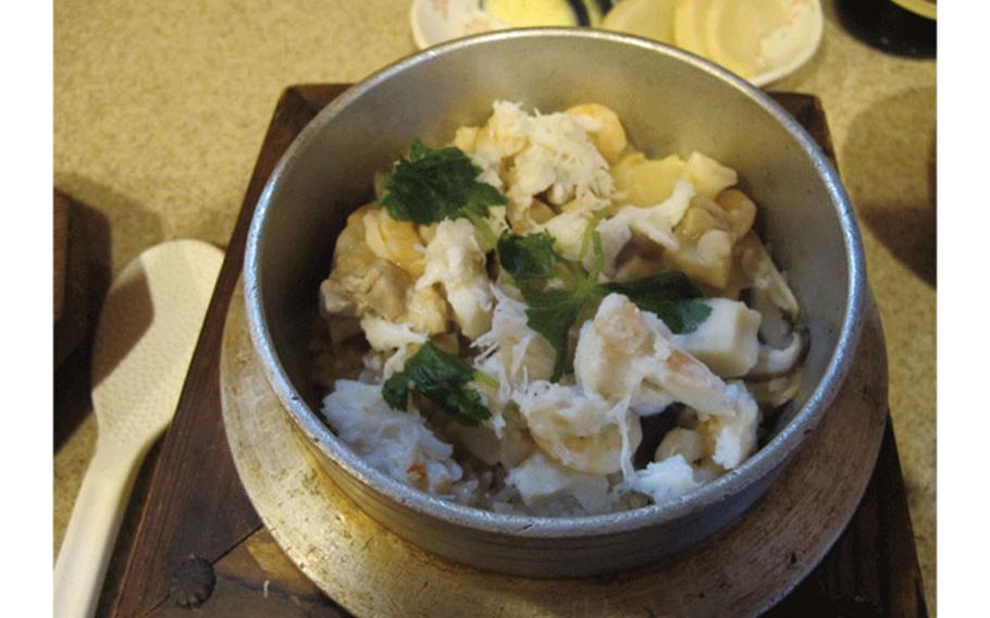 Kamameshi, a rice dish boiled with crab, chicken, and other ingredients in a small iron pot. 