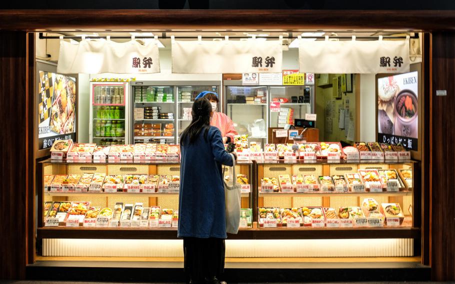 A Japanese customer buys a box of bento rice at Kyoto train station.