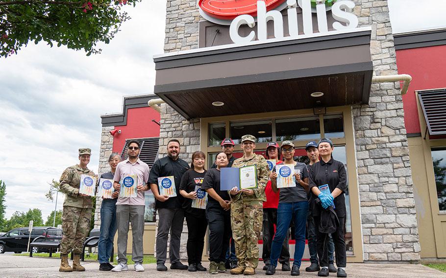 Chili’s Grill & Bar staff group photo as Stars and Stripes Pacific Commander Lt. Col. Marci Hoffman presents award.