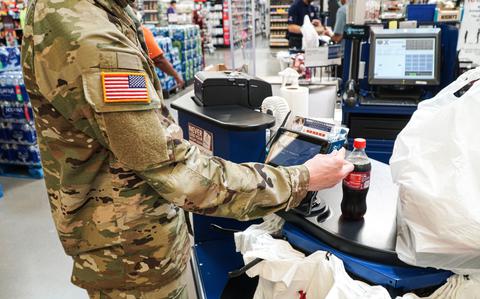 Photo Of A military personnel member purchasing a bottle of Coke at a supermarket.