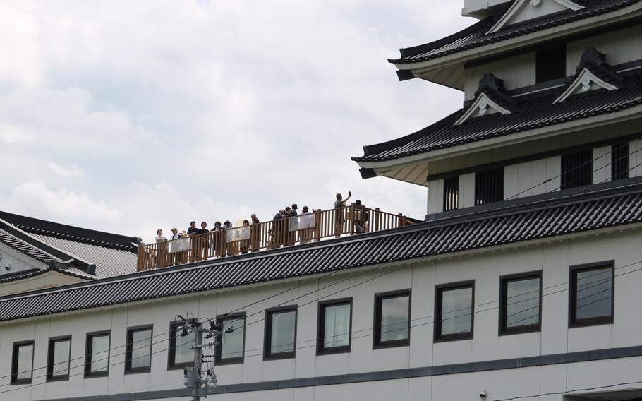 Visitors are enjoying the rice paddy art from the roof of a building.