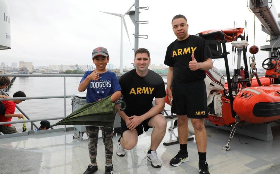 Soldiers assigned to the 5th Transportation Company at Yokohama North Dock pose for a photo together with a local child who was part of a group invited to the installation May 6 for an inaugural sports exchange event. 