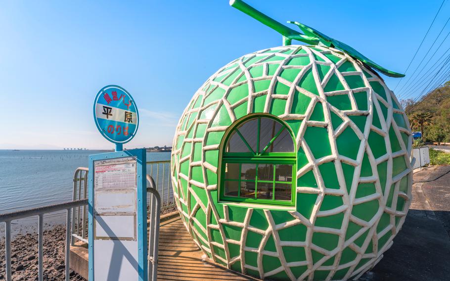 kyushu, japan - december 10 2021: Metal panel of the Hirahara bus stop on the Highway 207 of Konagai town in front of the famous giant cantaloupe fruit of the Tokimeki Fruit-shaped Bus Stop Avenue.