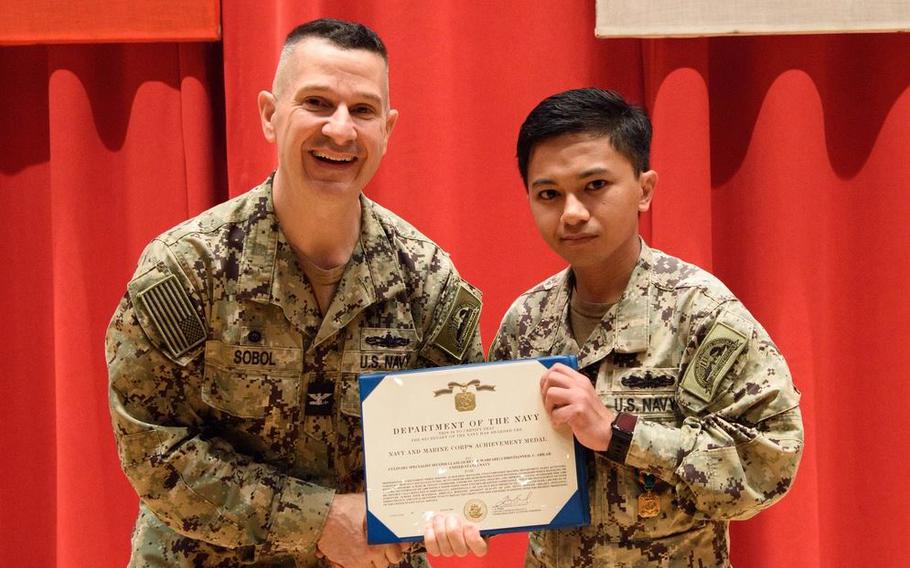 Culinary Specialist 2nd Class Christianneil C. Abilar receives a Navy and Marine Corps Achievement Medal from Commander, Fleet Activities Yokosuka (CFAY) Commanding Officer, Capt. Les Sobol.