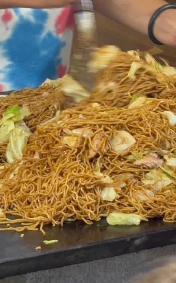 A booth staff member makes yakisoba.
