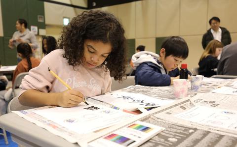 Photo Of American and Japanese children from Camp Zama and Sagamihara City write their names in calligraphy together.