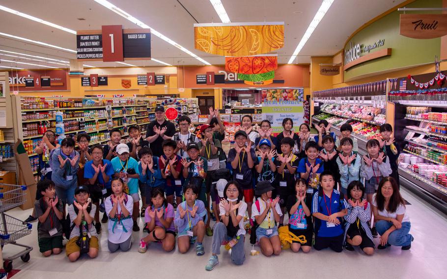 Towada Elementary School students and Misawa Commissary members pose for a photo after completing a Junior English tour at Misawa Air Base, Japan, July 23, 2024. The Misawa City Board of Education organizes an annual tour with the base for local students to sharpen their English and communication skills during summer break. 