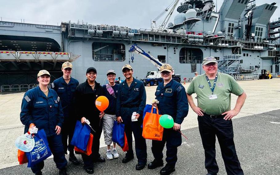 USS Tripoli servicemembers with USO volunteers Geri Haradon and Brent Frampton.
