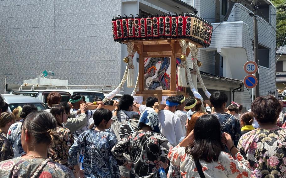 People lift a portable shrine onto their shoulders.
