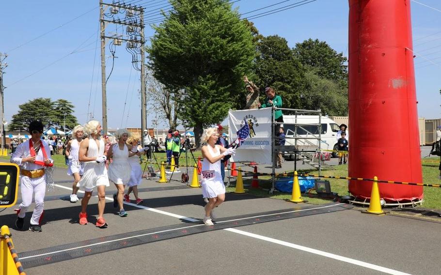 Runners in costume take off at the start of the 29th annual East Japan International Friendship Half Marathon April 27 on Sagami General Depot, Japan, while Command Sgt. Maj. Richard Meeker, top right, the senior enlisted leader of U.S. Army Garrison Japan, waves at them.
