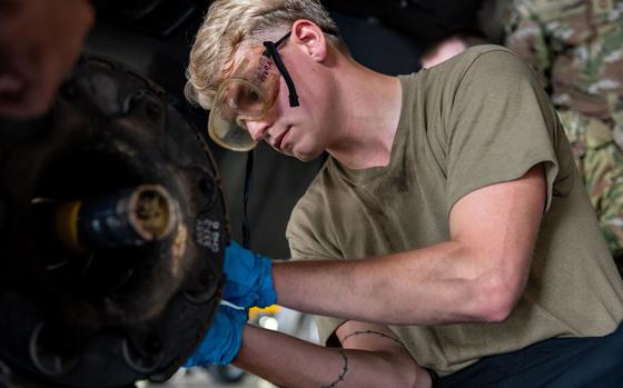 U.S. Air Force Senior Airman Derek Johnson loosens a bolt to remove a used F-16 brake pad.