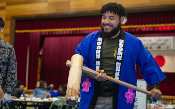 Photo Of Special Agent Rodriguez with Japanese traditional wear on holds a mallet during a mochi-pounding ceremony.