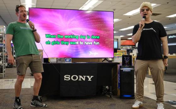Photo Of Capt. Les Sobol (right) and Cmdr. Patrick Gutierrez (left), Commander, Fleet Activities Yokosuka’s commanding officer and chief staff officer respectively, sing “Girls Just Want to Have Fun” at the Navy Exchange Yokosuka Karaoke Roadshow June 14, 2024. The installation’s leadership were among several participants in the exchange’s event. 