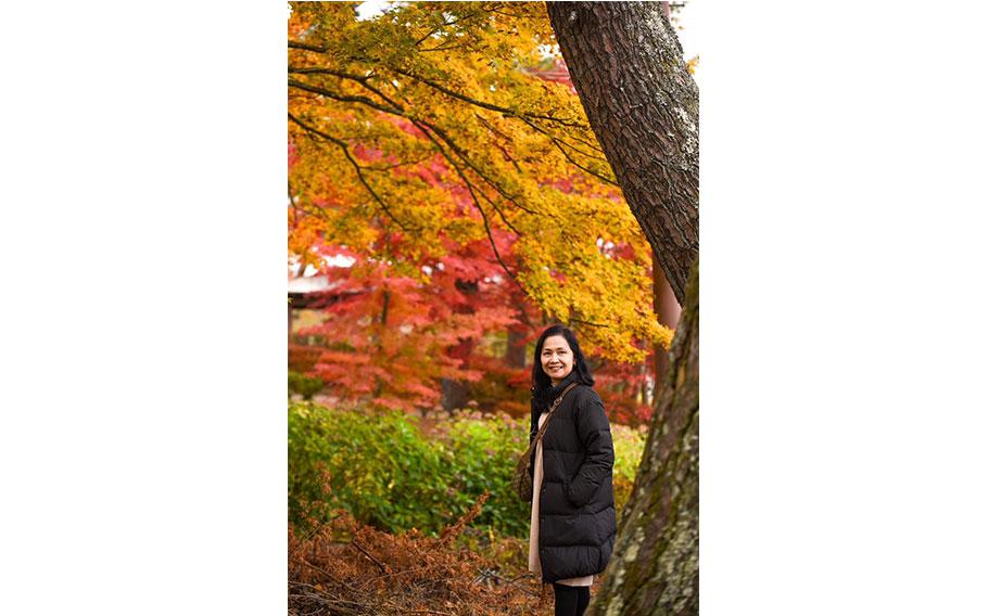 A woman is enjyoing autumn leaves.