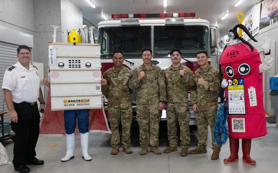 Photo Of Airmen from the 374th Civil Engineer Squadron (CES)pose for a photo during a Tokyo Fire Prevention Week event at the Fussa Fire Station in Fussa City, Japan, Aug. 24, 2024. The 374th CES provided two static display fire engines for the event and handed out plastic firefighter helmets to the Fussa community. 