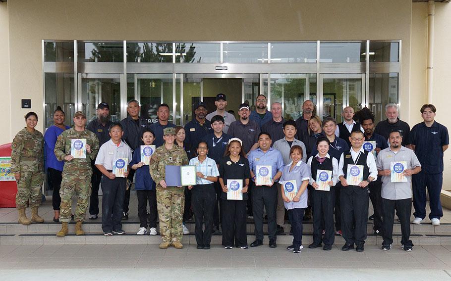 Yokota Kanto Lodge staff group photo as Stars and Stripes Pacific Commander Lt. Col. Marci Hoffman presents award.