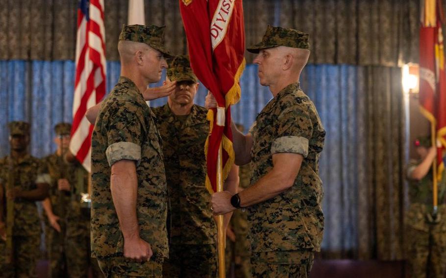 U.S. Marine Corps Maj. Gen. Christian Wortman, right, outgoing commanding general of 3d Marine Division, passes the division colors to Maj. Gen. Kyle Ellison, incoming commanding general of 3DMARDIV, during a change of command ceremony.