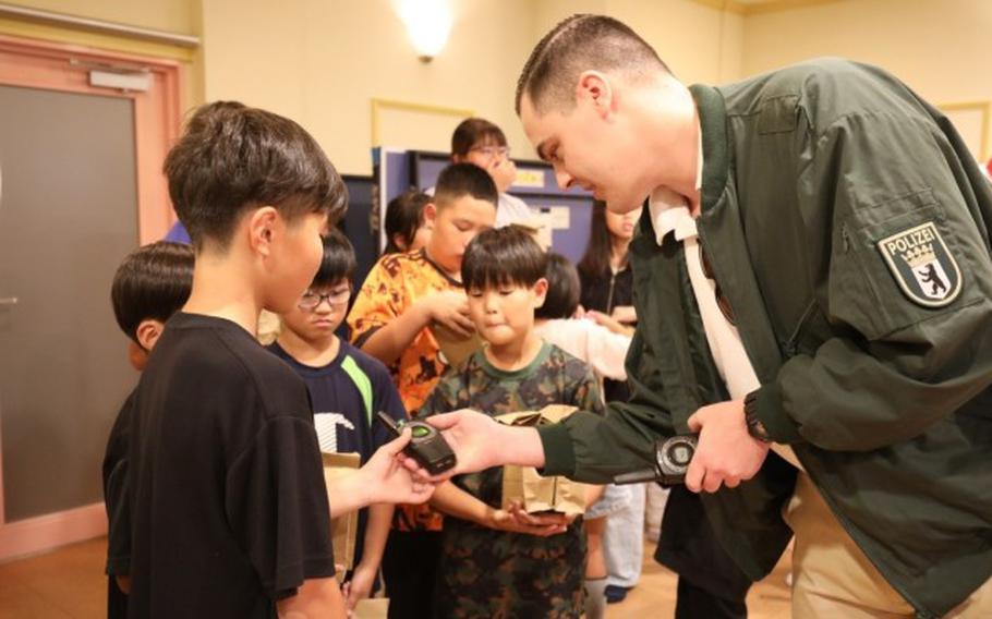 Staff Sgt. Brian Hanson shows his radio transceiver to residents at the nearby Seiko Gakuen children’s home.