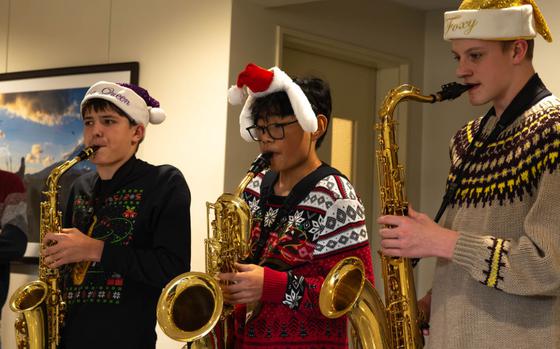 Photo Of Three Yokota High School students with a hat lifted spirits with festive saxophone melodies.